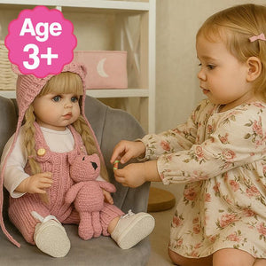 Toddler playing with a lifelike Real-Feel Baby Doll wearing a pink knitted outfit and hat, suitable for ages 3 and up