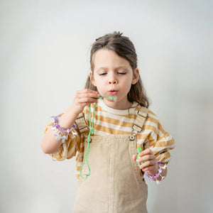 child wearing bracelet-making kit bracelets blowing bubbles creative kids craft activity