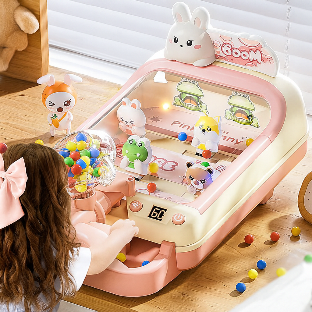 Child playing with pink and white children's marble shooting game machine featuring cute animal characters and colorful marbles indoors