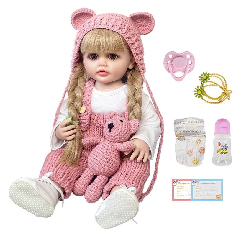 Real-feel baby doll with blonde hair, pink knit outfit, and full care accessories including pacifier, bottle, diaper, toy, and birth certificate